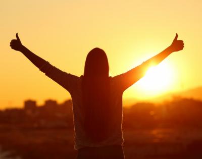 silhouette of person standing in sunset with thumbs up