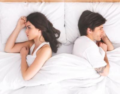 Unhappy couple laying in bed facing away from each other