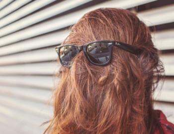 Woman with her hair in her face wearing sunglasses